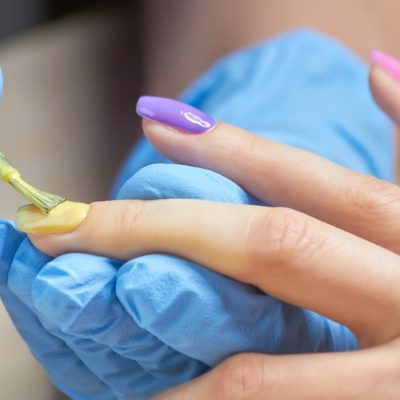 Manicure specialist applying varnish to client Manicure specialist applying varnish to client